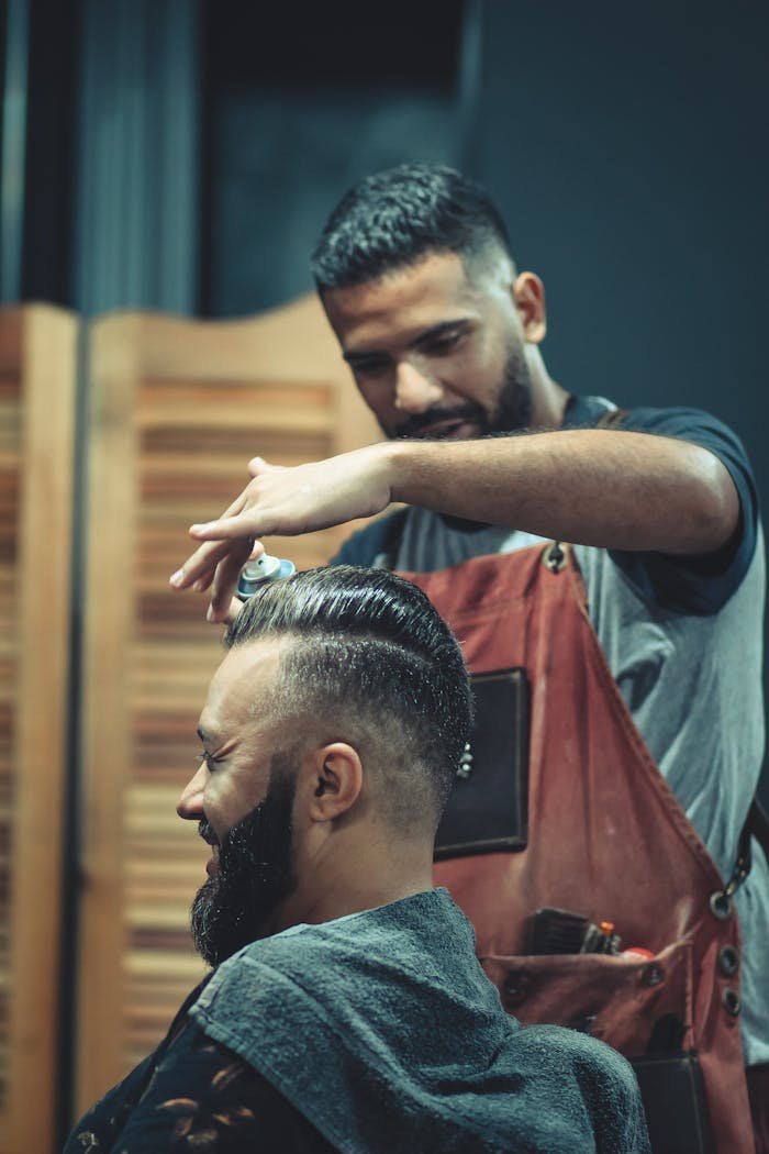 Skilled barber styling a mans hair in a modern barbershop setting, creating a trendy look.