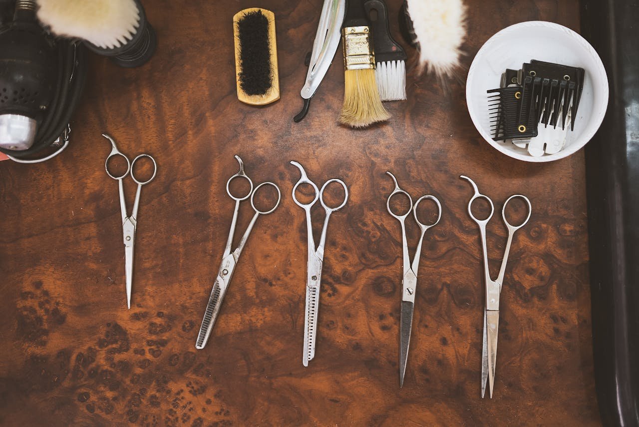 A collection of vintage barber tools including scissors and brushes on a wooden surface.